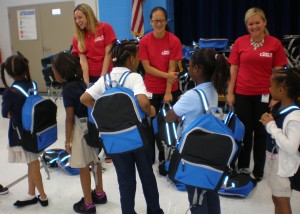 Fluor Cares volunteers are shown distributing backpacks to students at Hunters Glen Elementary School. 